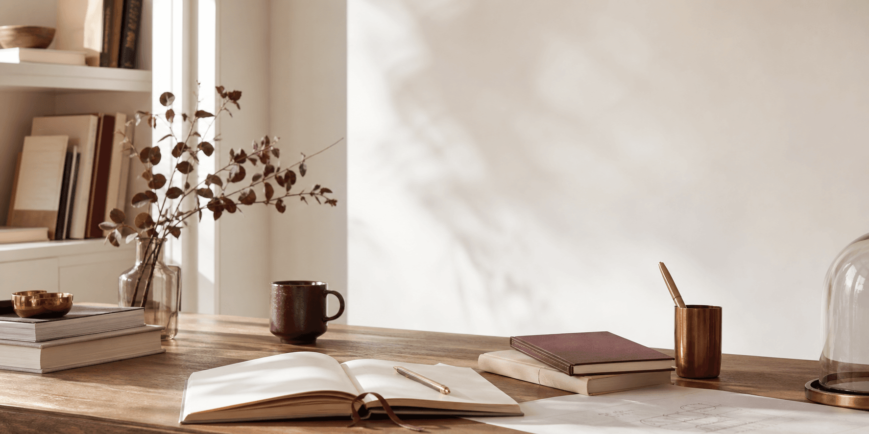Mesa editorial clara com livros, caderno e detalhes em cobre